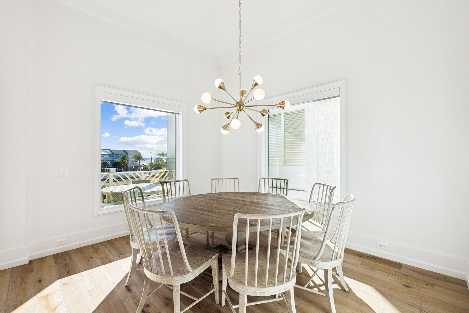 Gather around the elegant dining table where memorable meals unfold, with natural light streaming through windows overlooking the scenic coastline.