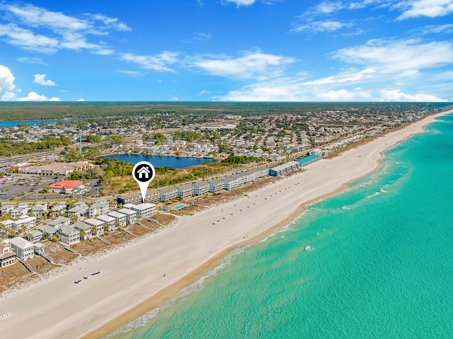 Aerial view of a beachfront vacation rental property nestled between pristine turquoise waters and tranquil coastal surroundings, offering convenient access to sandy shores and nearby amenities.