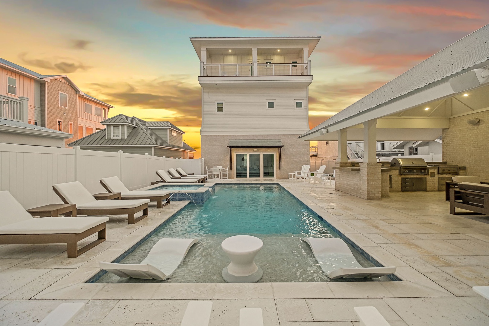 Stunning modern property with private pool, outdoor kitchen, and rooftop deck under beautiful sunset skies.