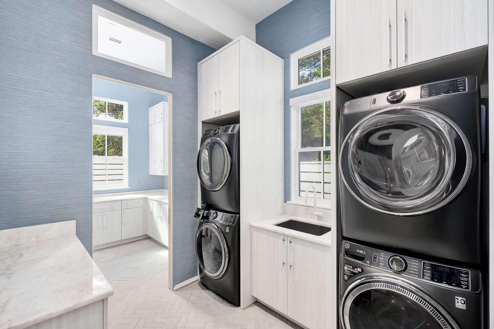 Laundry day just got easier in this bright, beautifully designed space with modern front-load washers and dryers and ample storage to keep everything organized.