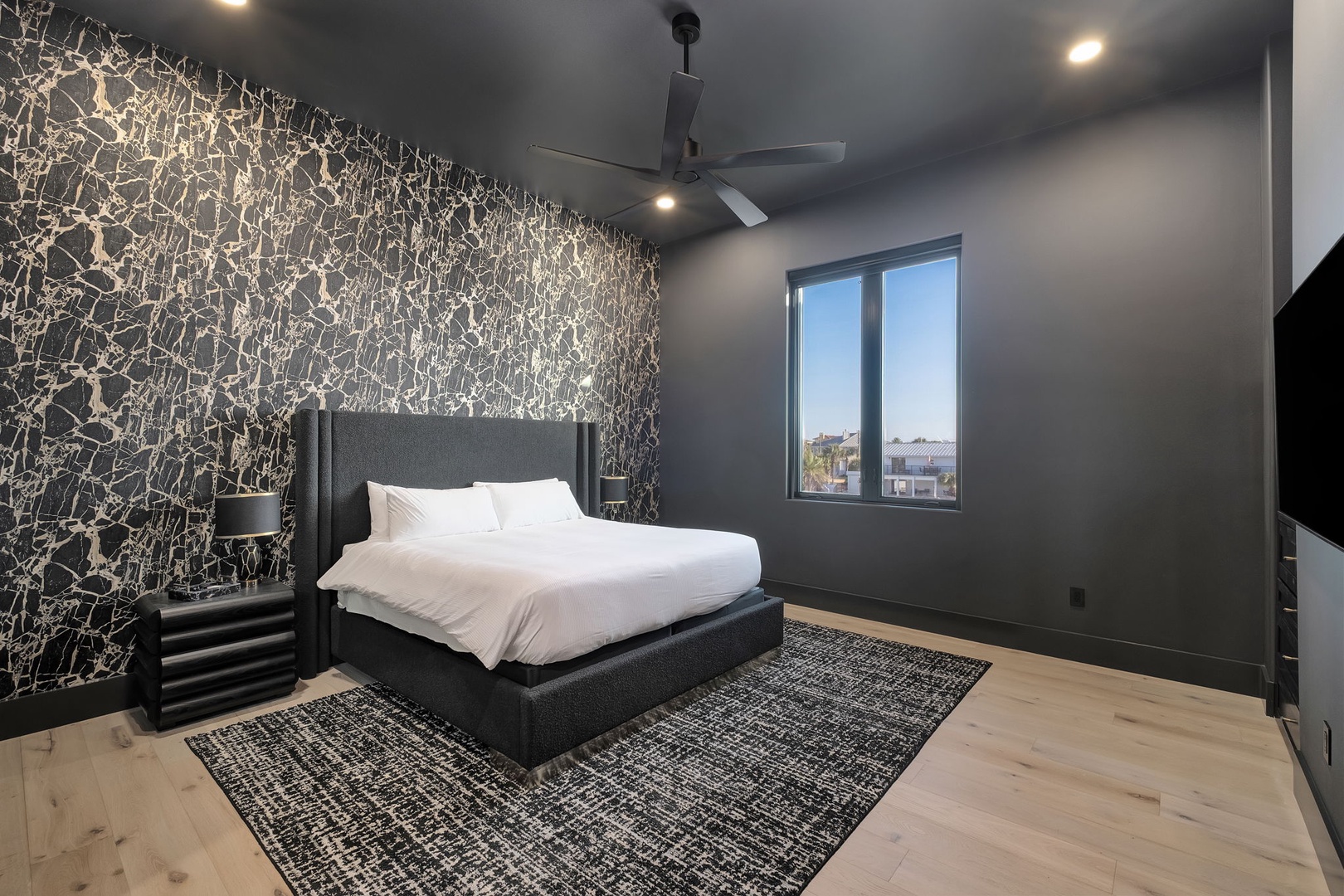 Your stylish bedroom features crisp white linens and striking modern art, with a ceiling fan for comfort and city views from your window.