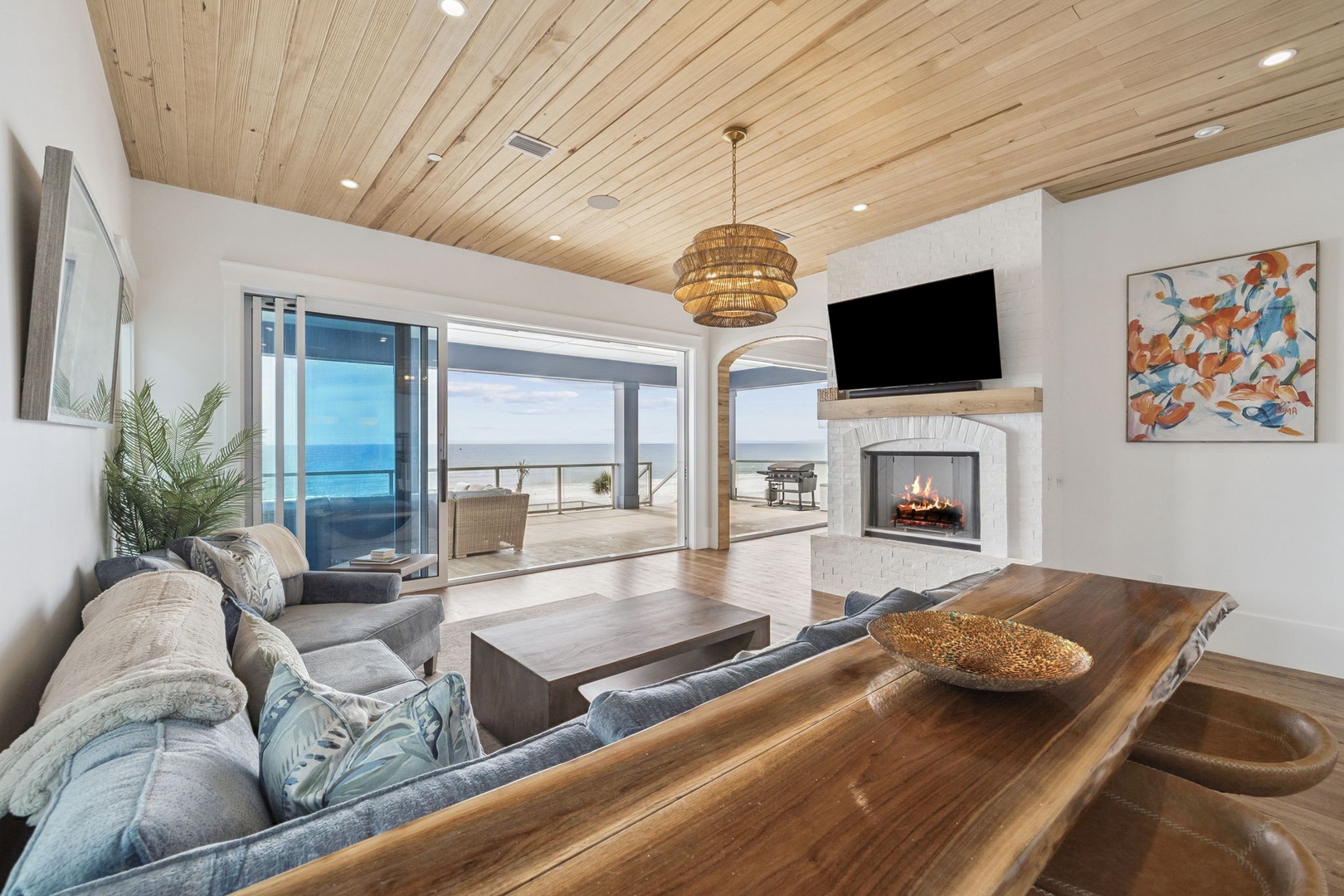 Relax in your coastal living room where warmth meets elegance—plush seating, crackling fireplace, and ocean views create the perfect retreat.