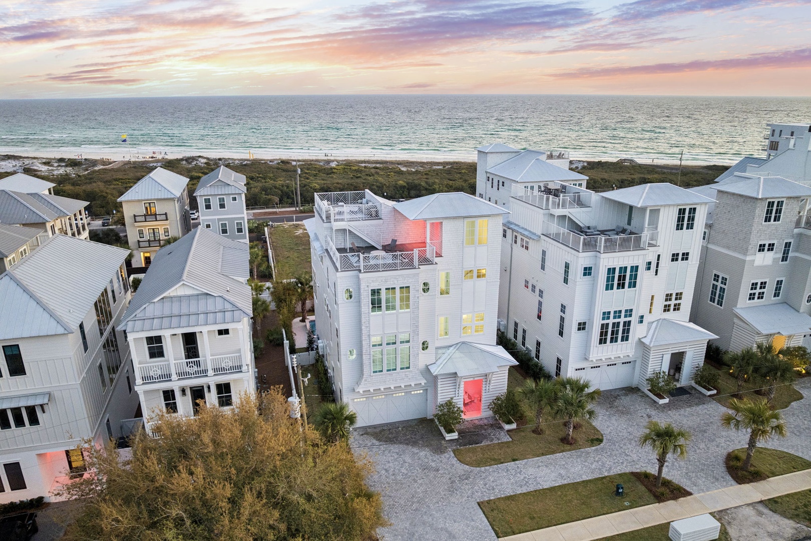 Coastal neighborhood with modern beach houses just steps from the shore, featuring stunning sunset views over the ocean.