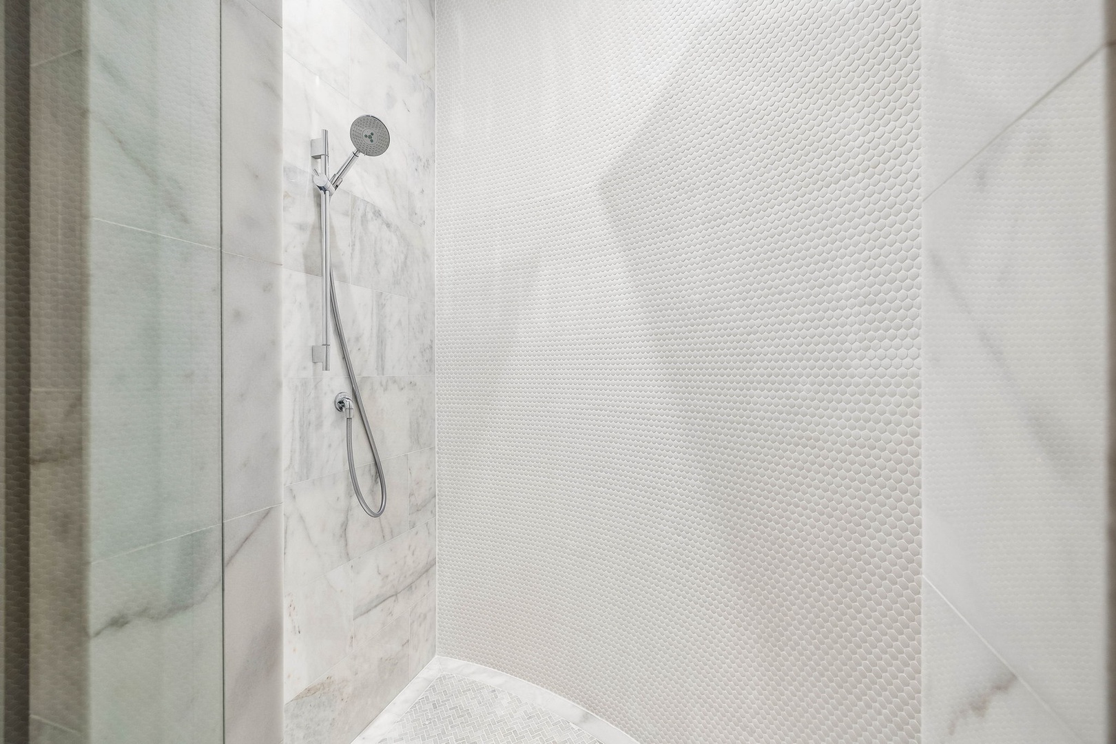 Step into your private sanctuary with a sleek walk-in shower featuring elegant marble-look tile and a modern handheld showerhead for a refreshing and customizable experience.