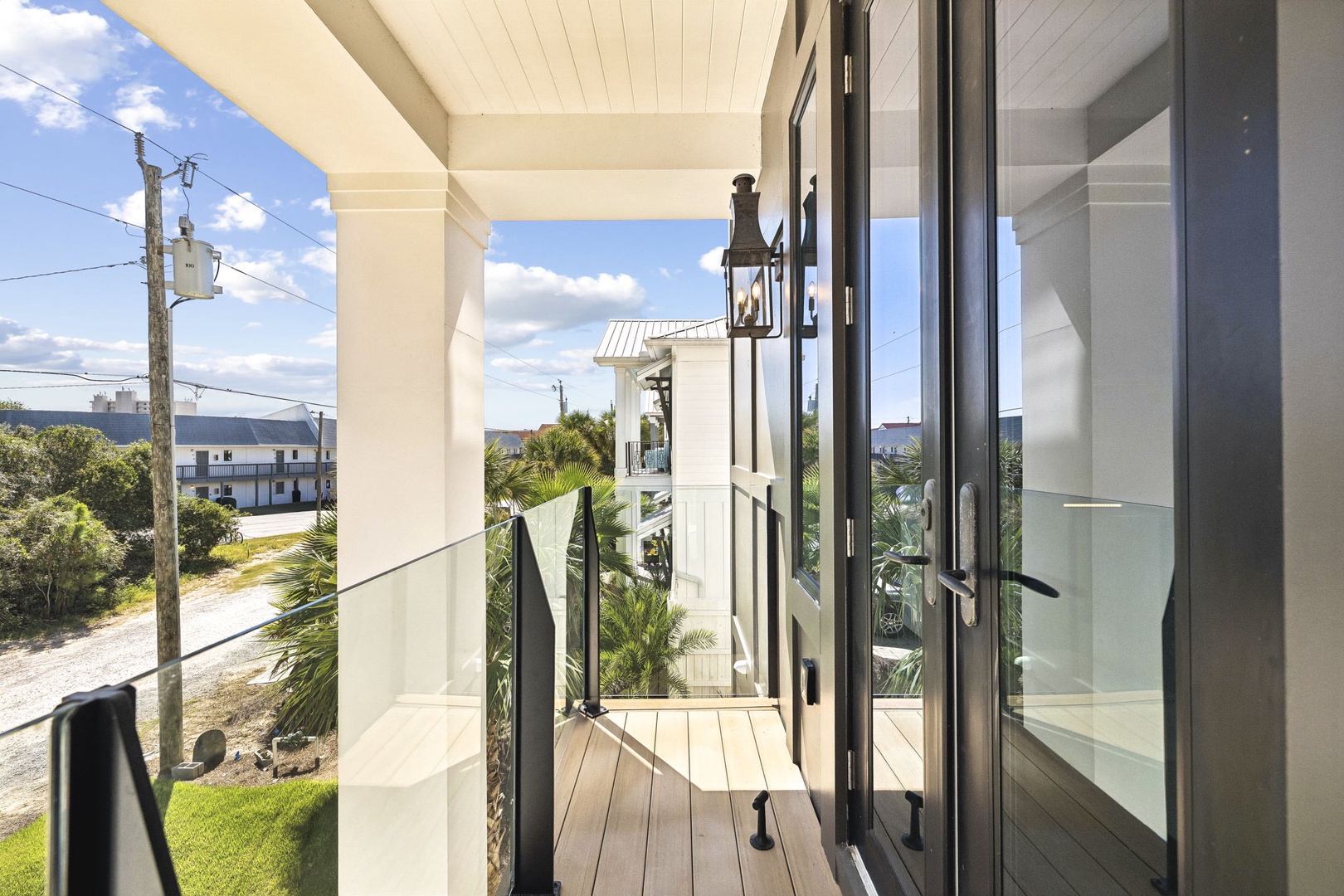 Step through these glass doors onto a peaceful covered porch, where coastal breezes meet your morning coffee and distant views of neighboring homes remind you this tranquil escape is just moments from local charm.