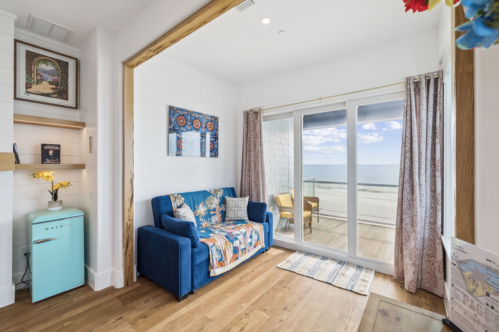 Your bright living space opens to stunning sea views through sliding glass doors, where colorful decor meets coastal comfort.