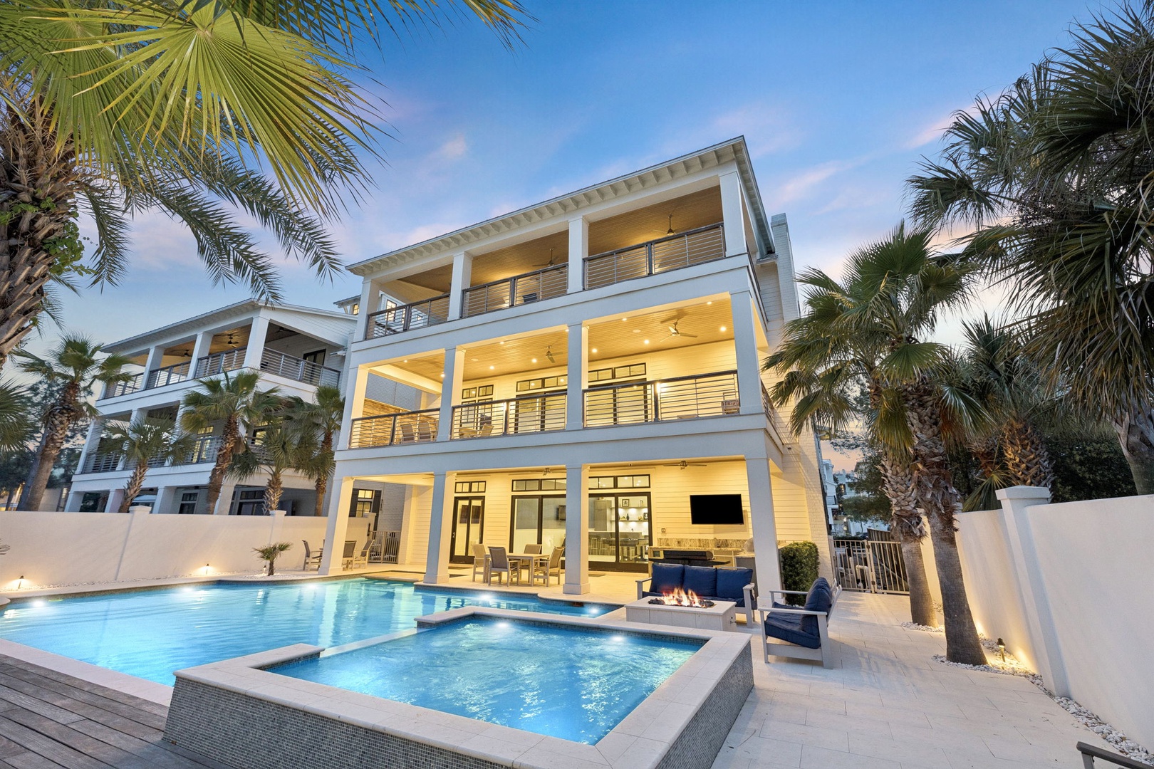 Modern luxury villa with pristine swimming pool and hot tub, surrounded by swaying palm trees in an upscale tropical setting.