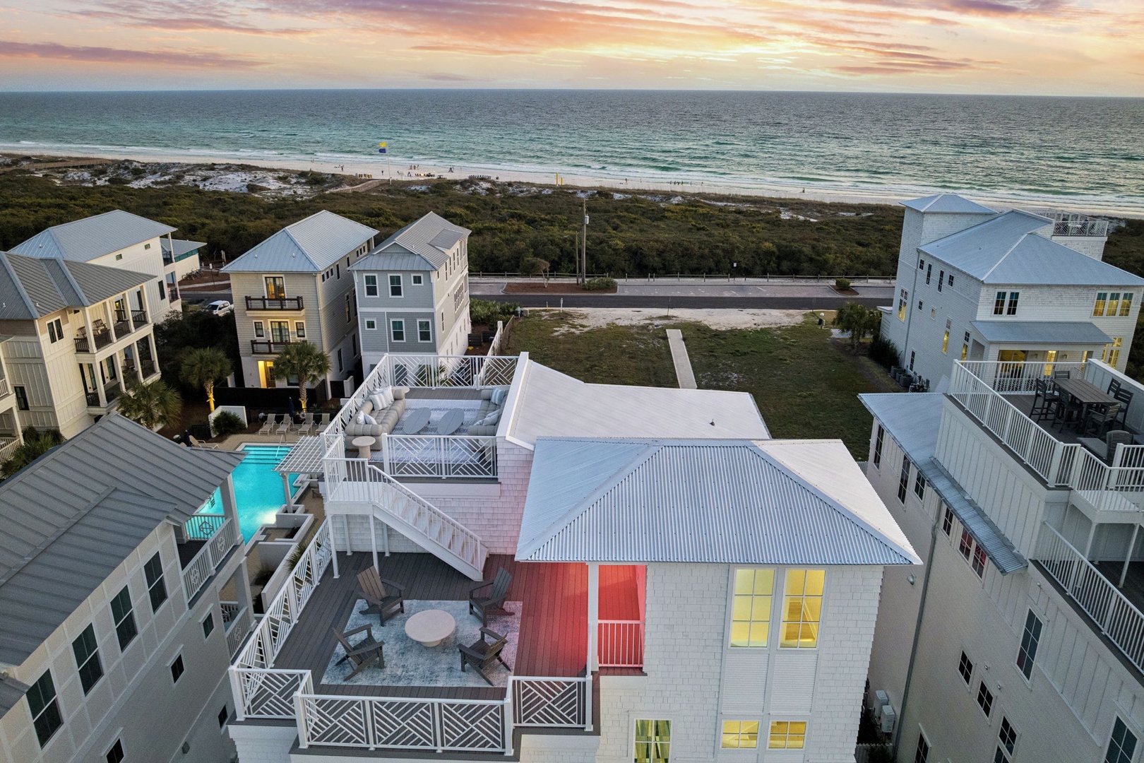 Coastal vacation homes with swimming pools nestle among lush vegetation, just steps from pristine beaches and endless ocean views at sunset.