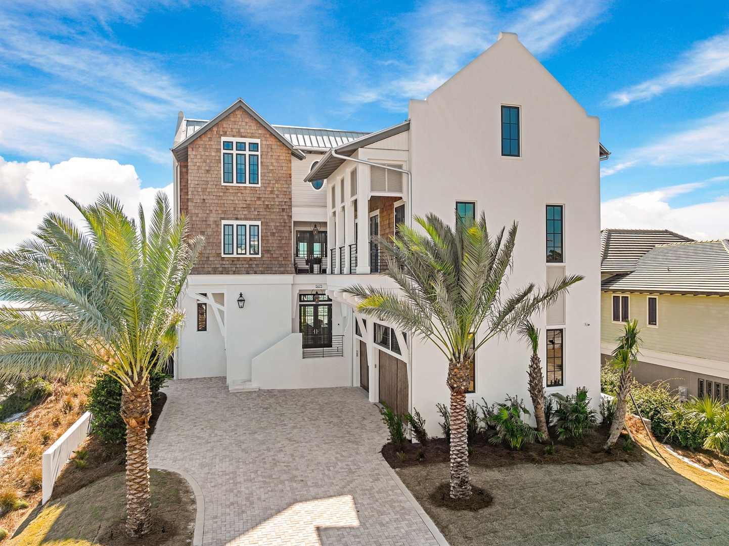 Stunning three-story coastal property with palm trees and elegant architecture in a peaceful neighborhood setting.