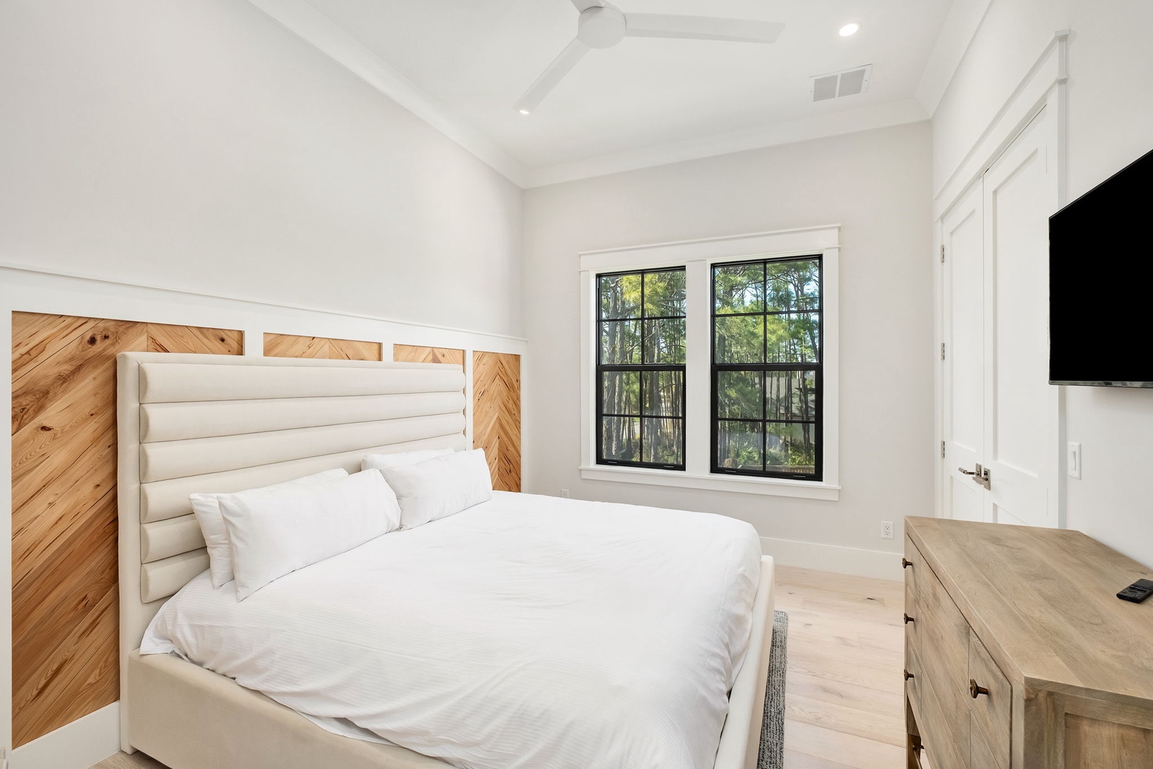 Sink into crisp white linens and wake to leafy views through your private window in this serene bedroom sanctuary.