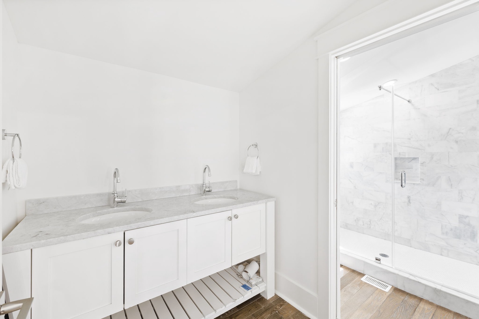 Step into your pristine marble bathroom featuring dual vanities and a luxurious glass-enclosed shower for ultimate relaxation.