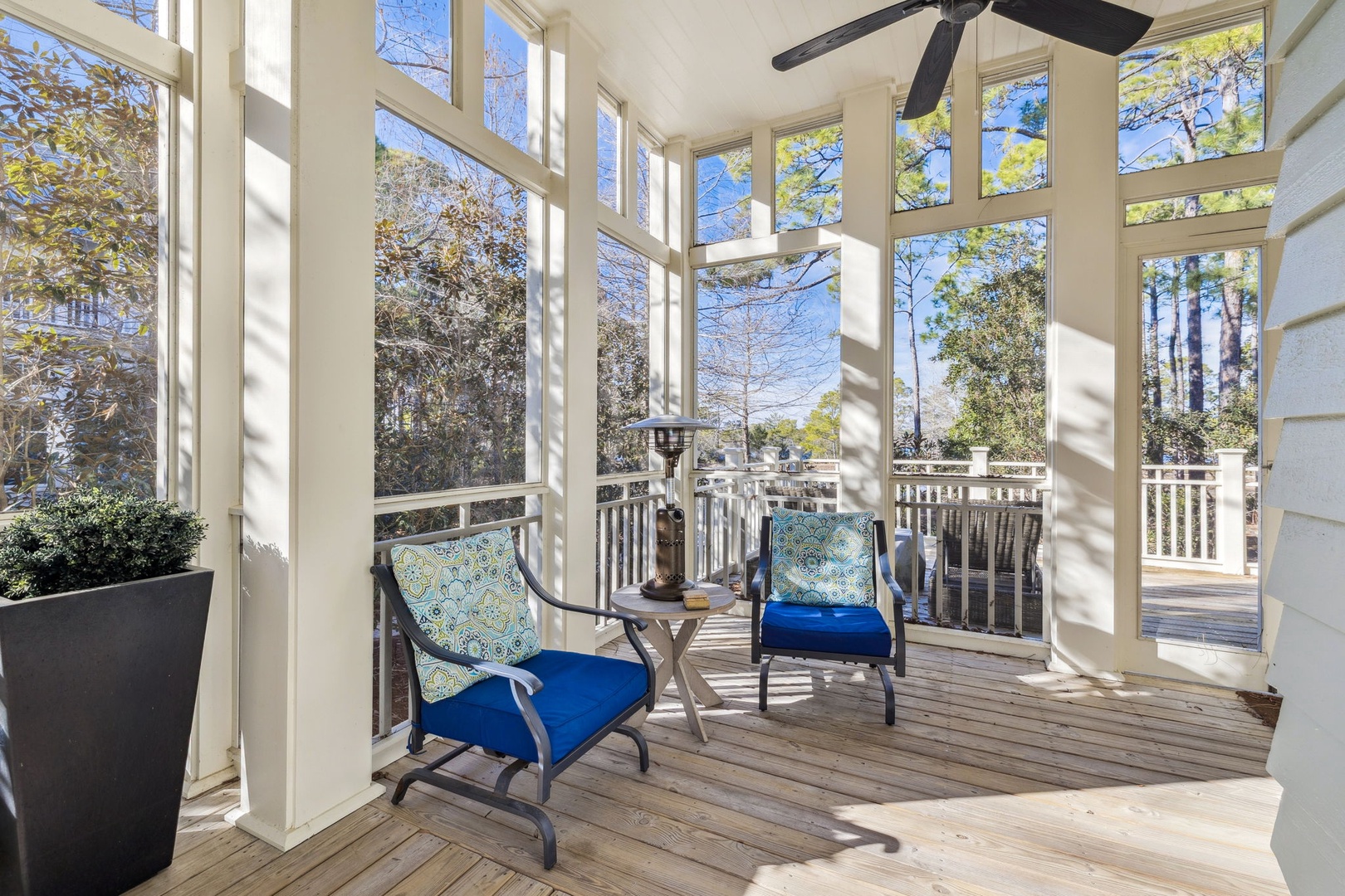 Relax in your bright screened porch with comfy seating and peaceful tree views—the perfect spot for morning coffee.