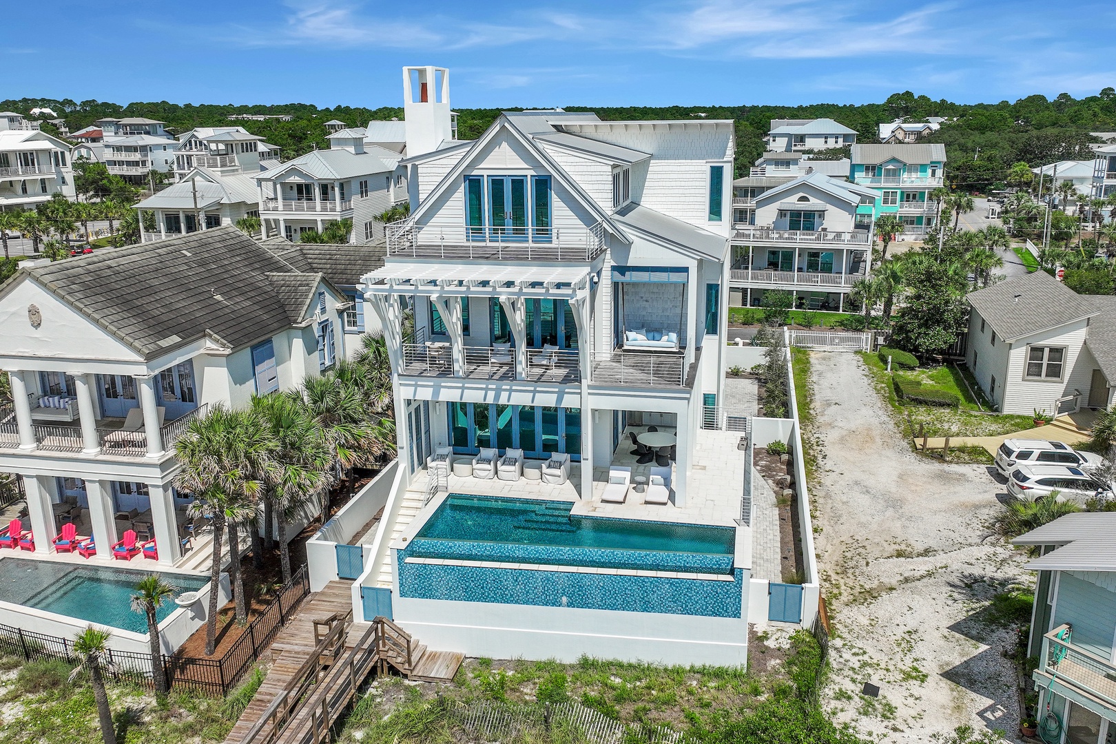 A stunning coastal residence in a beach neighborhood, featuring modern architecture with a private pool surrounded by palm trees and neighboring vacation homes.