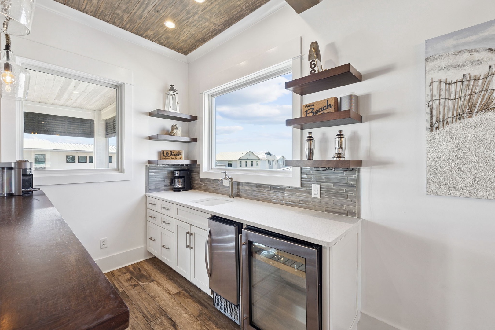 Your stylish kitchen features coastal charm with white cabinets, floating shelves, and beach-themed decor creating the perfect space for vacation cooking.