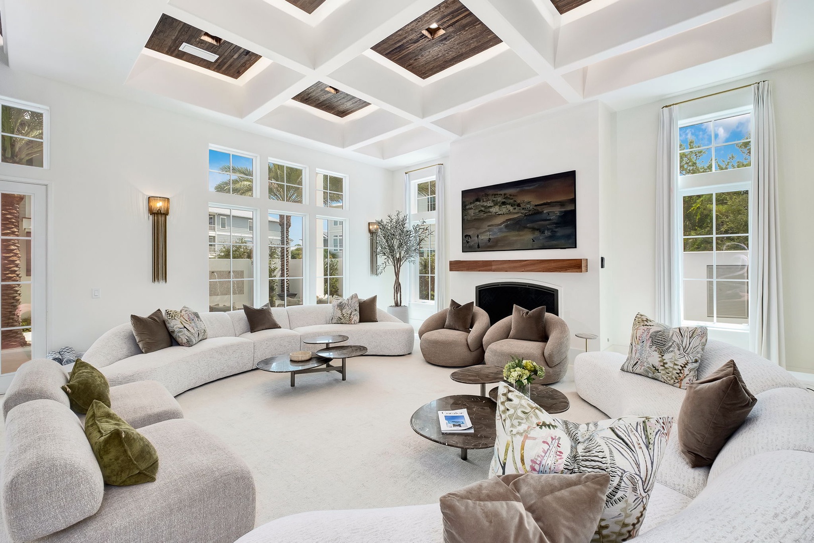 Sink into plush seating beneath soaring coffered ceilings in this airy living space. Natural light pours through tall windows, highlighting the warm fireplace and elegant design that invites you to relax in comfort.