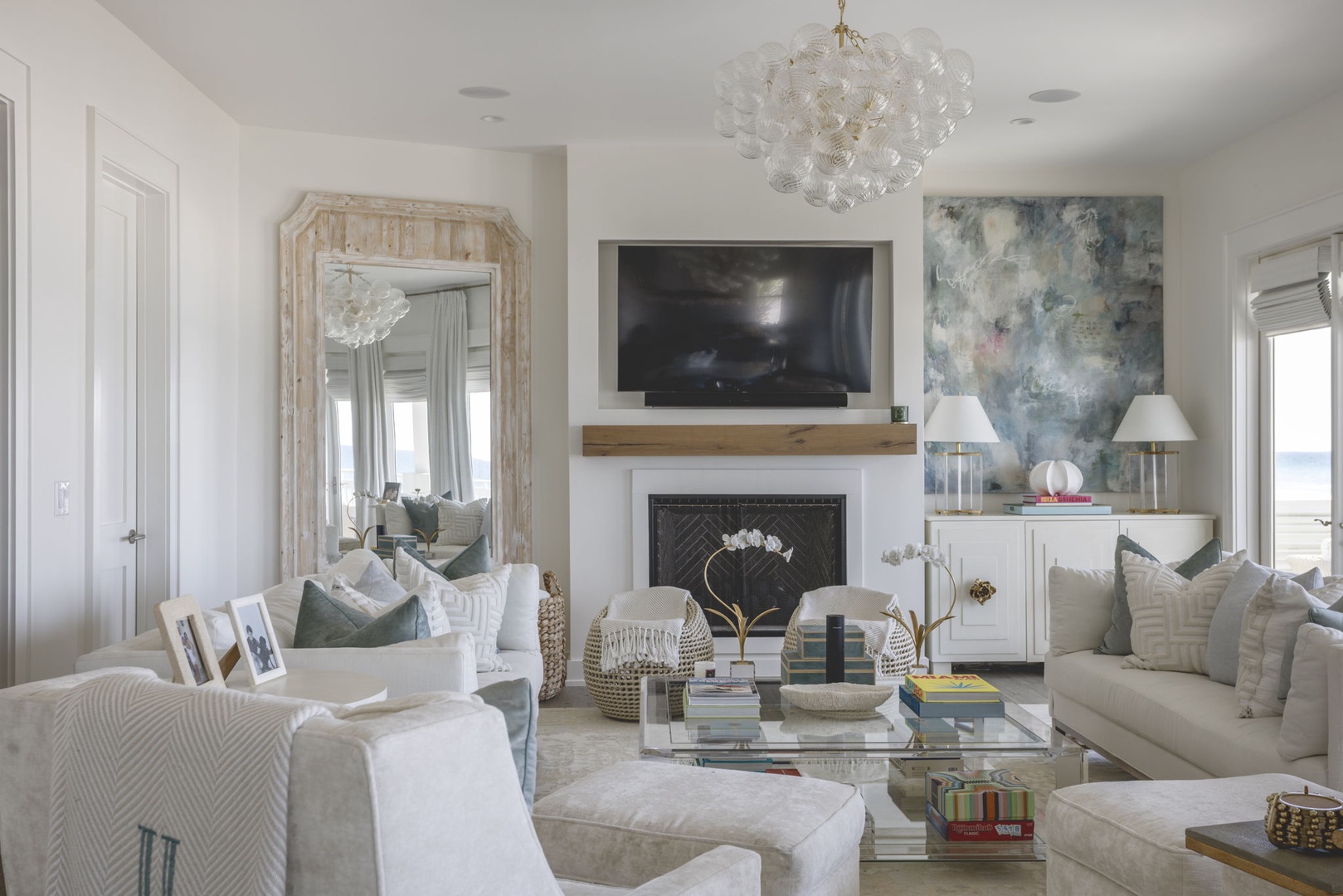 Sink into plush seating and unwind in this elegantly styled living room, where a cozy fireplace, coastal artwork, and soft lighting create your perfect retreat.
