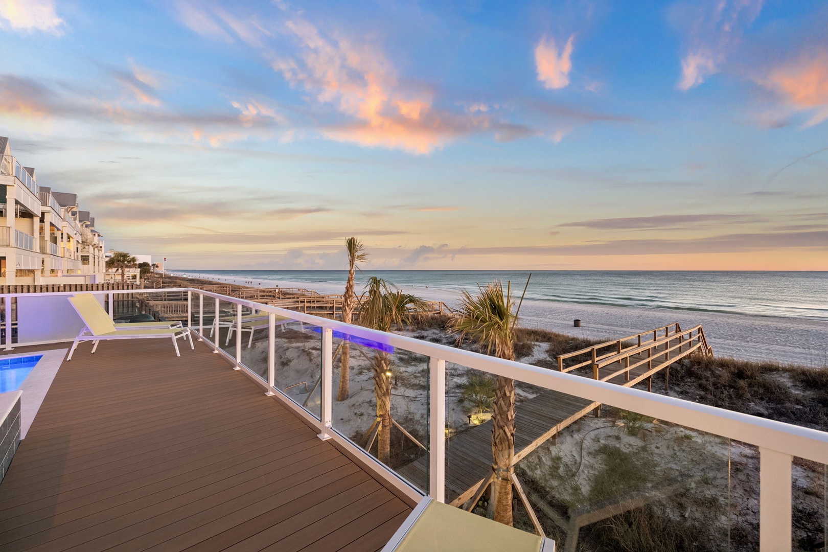 Stunning beachfront balcony with white sand and ocean views at sunset.
