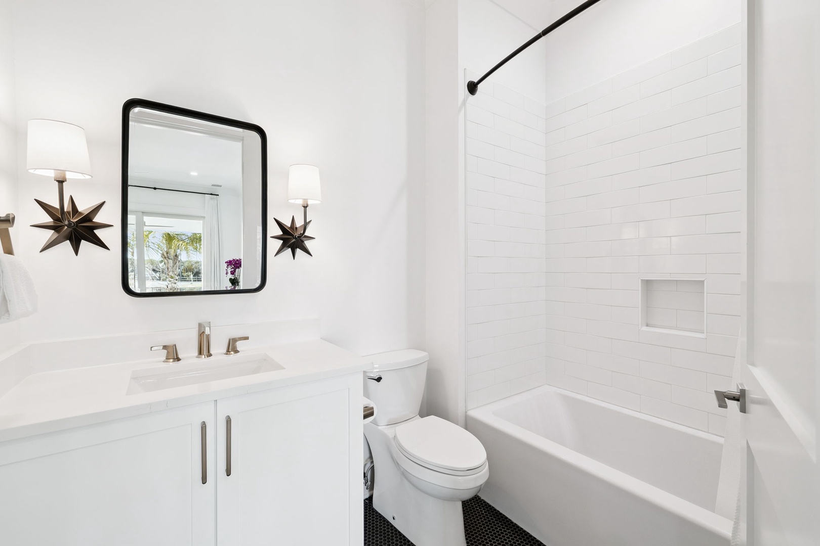 Step into your crisp, modern bathroom featuring elegant star-light sconces and a relaxing tub for unwinding after your adventures.