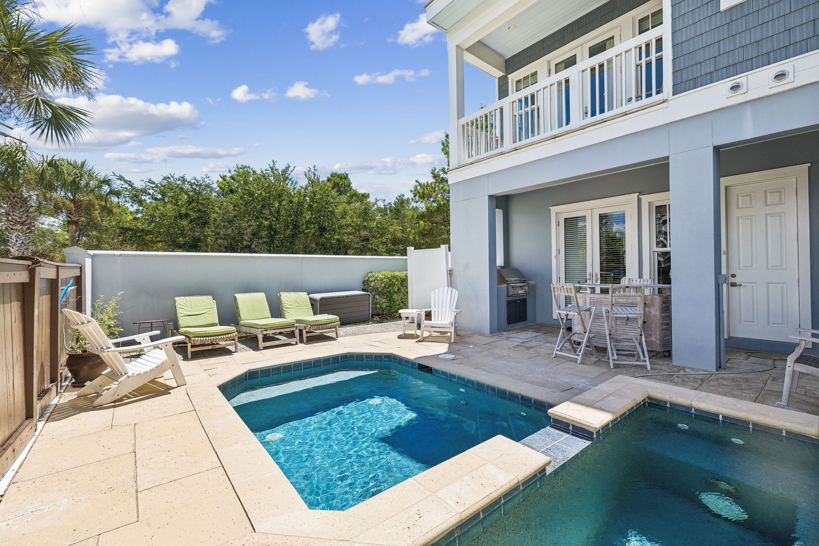 A private backyard oasis awaits with a sparkling pool and hot tub, surrounded by comfortable lounge chairs and shaded seating. Your perfect spot to unwind under clear coastal skies.