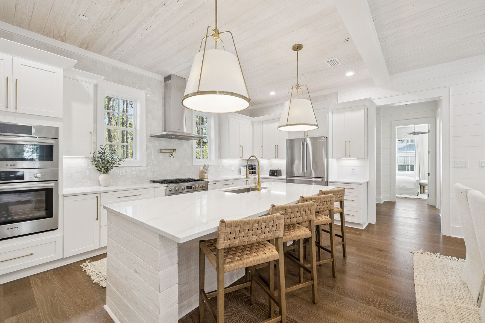 Cook memorable meals in your stunning gourmet kitchen featuring gleaming white countertops, brass pendant lights, and premium appliances.
