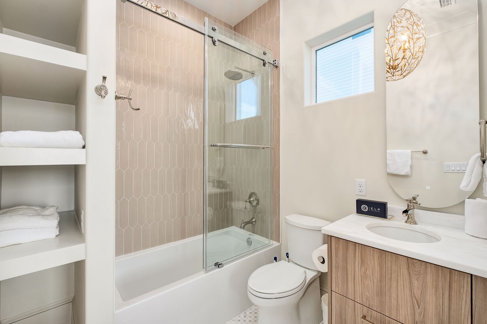 Step into your spa-like bathroom with soft neutral tones and elegant geometric tile. Fluffy towels await on open shelves, while natural light brightens your space for a refreshing, relaxing retreat.