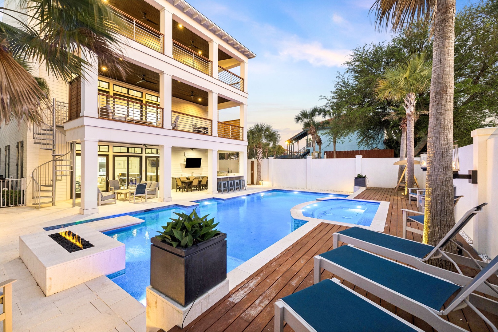 Modern beachfront villa with sparkling pool and hot tub surrounded by swaying palms at golden hour.