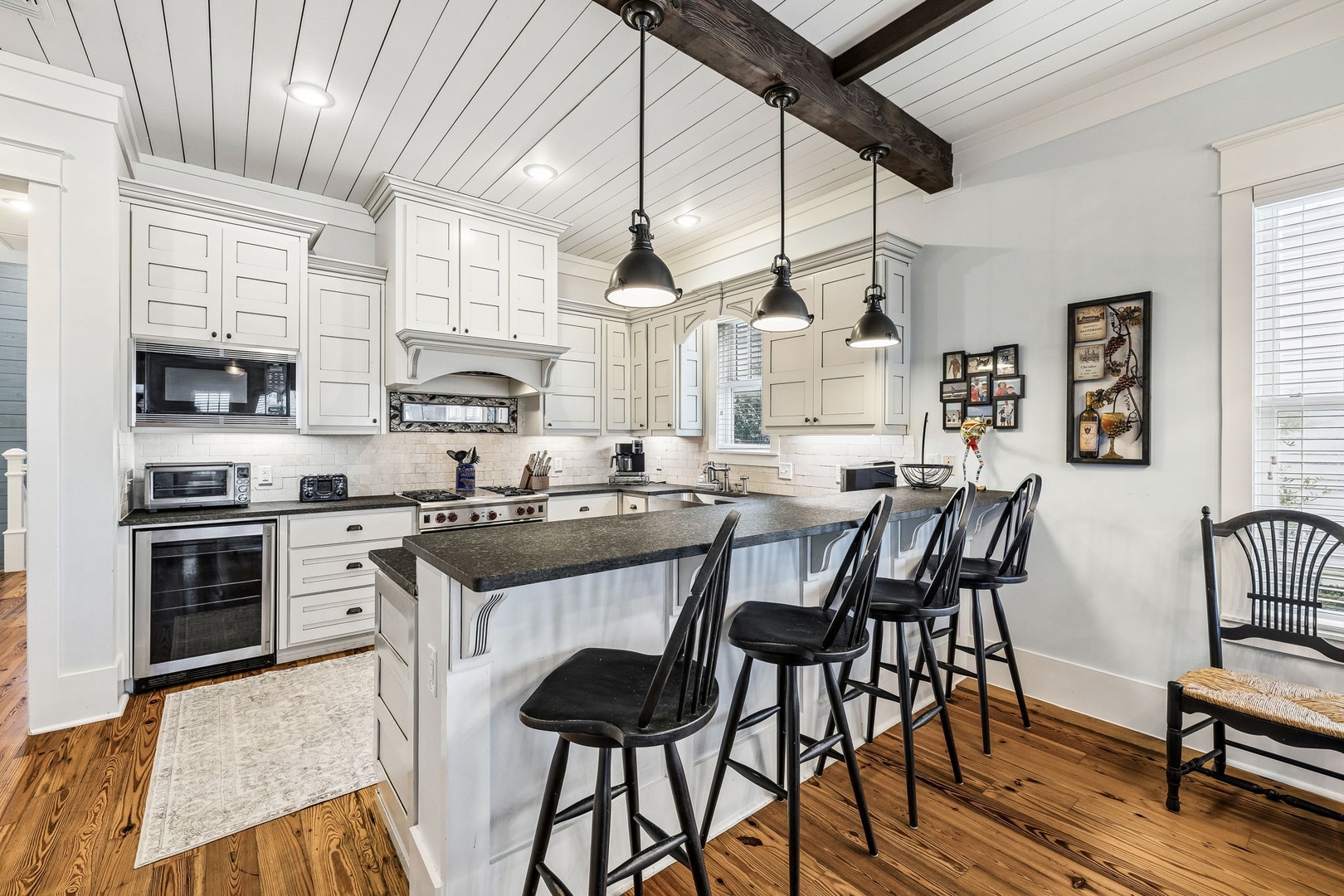 Gather around the spacious island in this farmhouse-style kitchen, where rustic beams and pendant lights set the perfect stage for morning coffee and shared meals with loved ones.