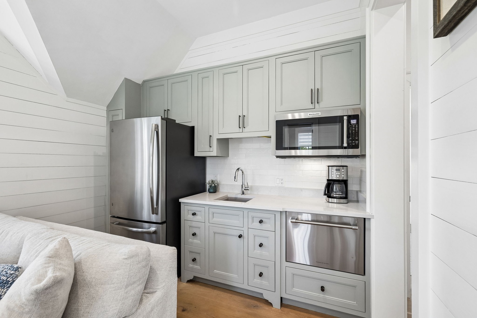 Your cozy kitchenette features sage-green cabinetry, stainless steel appliances, and a sleek quartz countertop—perfect for whipping up morning coffee or a quick meal.