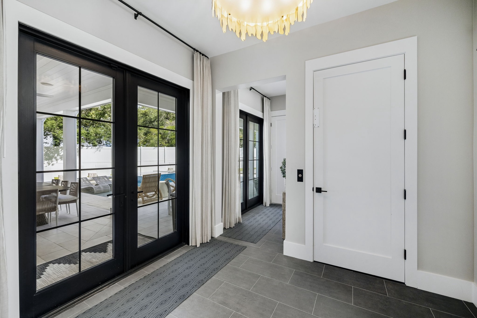 Step into a bright, welcoming entryway where natural light pours through elegant glass doors, inviting you straight out to your private patio and pool area—your vacation sanctuary awaits just beyond.