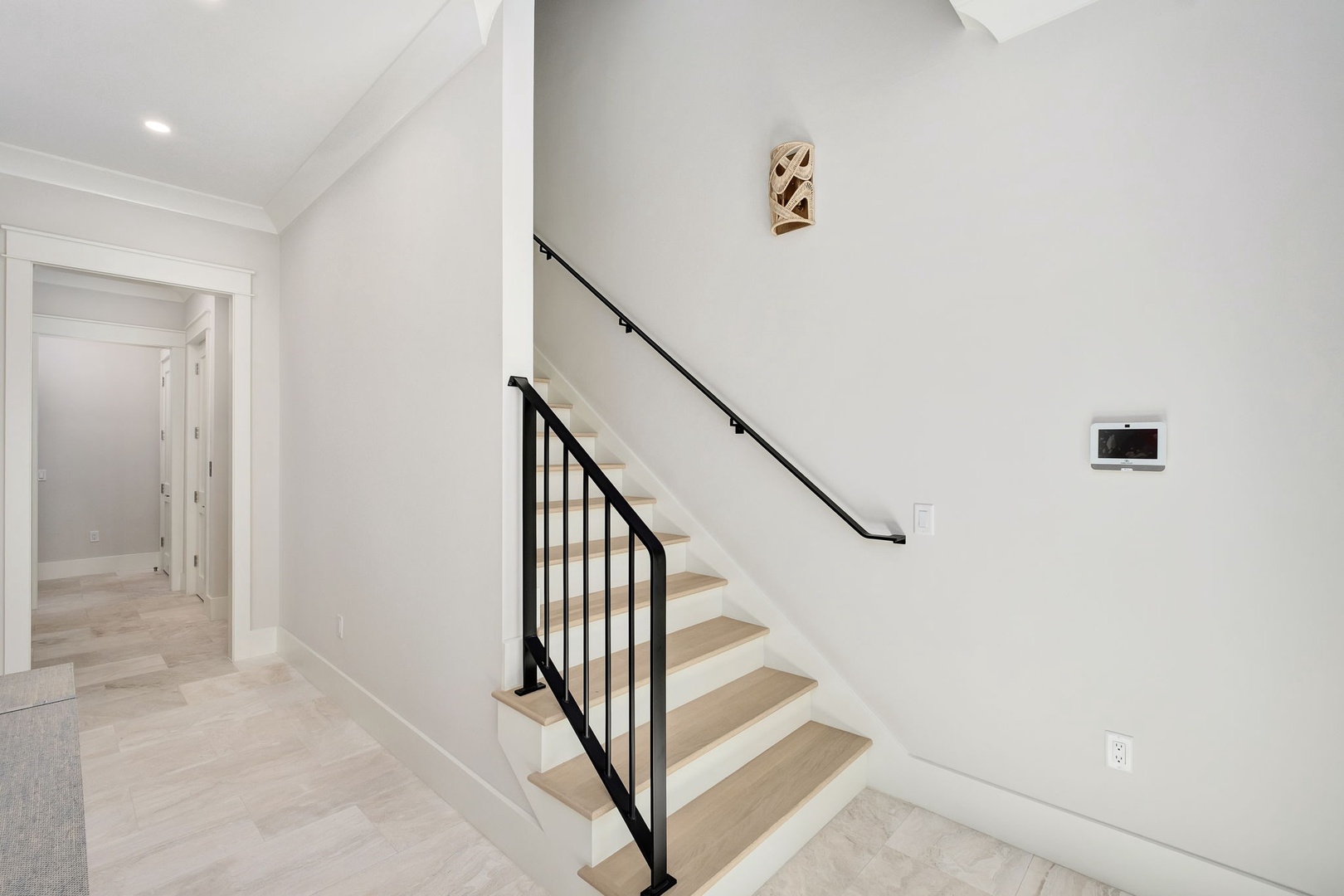 Your private staircase features sleek black railings and warm wood steps, connecting you to upper-level bedrooms in this modern home.