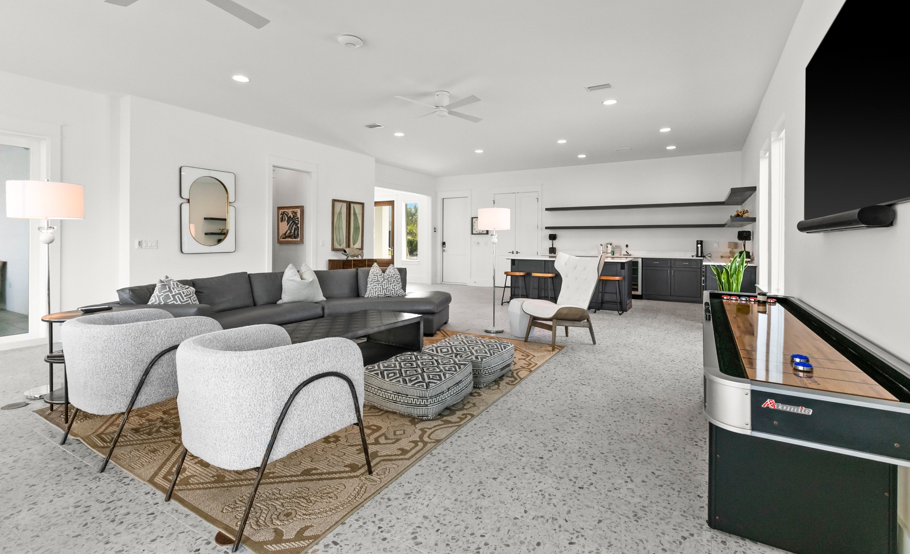 Settle into this spacious open-concept living area where modern design meets comfort. Your group can gather around the sectional, unwind in stylish accent chairs, or shoot a game at the vintage arcade table.