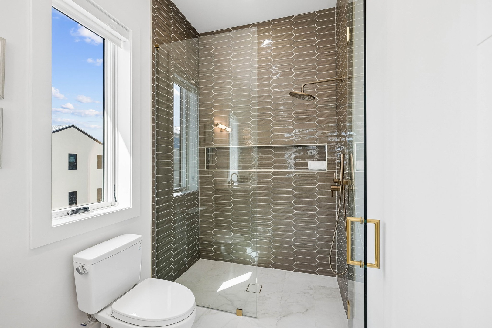 Step into your spa-like bathroom with a beautiful walk-in shower featuring elegant geometric tile and gleaming glass doors. The modern fixtures and bright natural light create a refreshing retreat.
