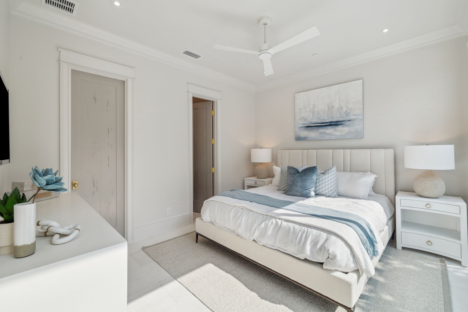 Your peaceful bedroom features a plush bed dressed in crisp linens and coastal-inspired accents, with serene artwork and soft bedside lamps creating a calming retreat for restful nights.