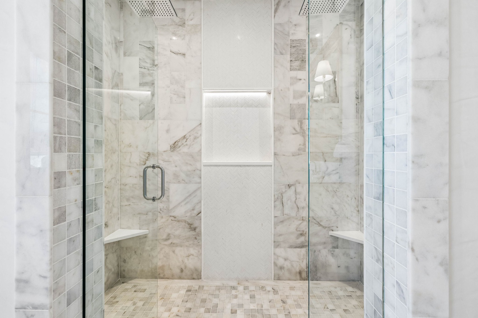 Step into this luxurious marble walk-in shower with dual rainfall heads and built-in benches, where every detail invites you to unwind in spa-like comfort.