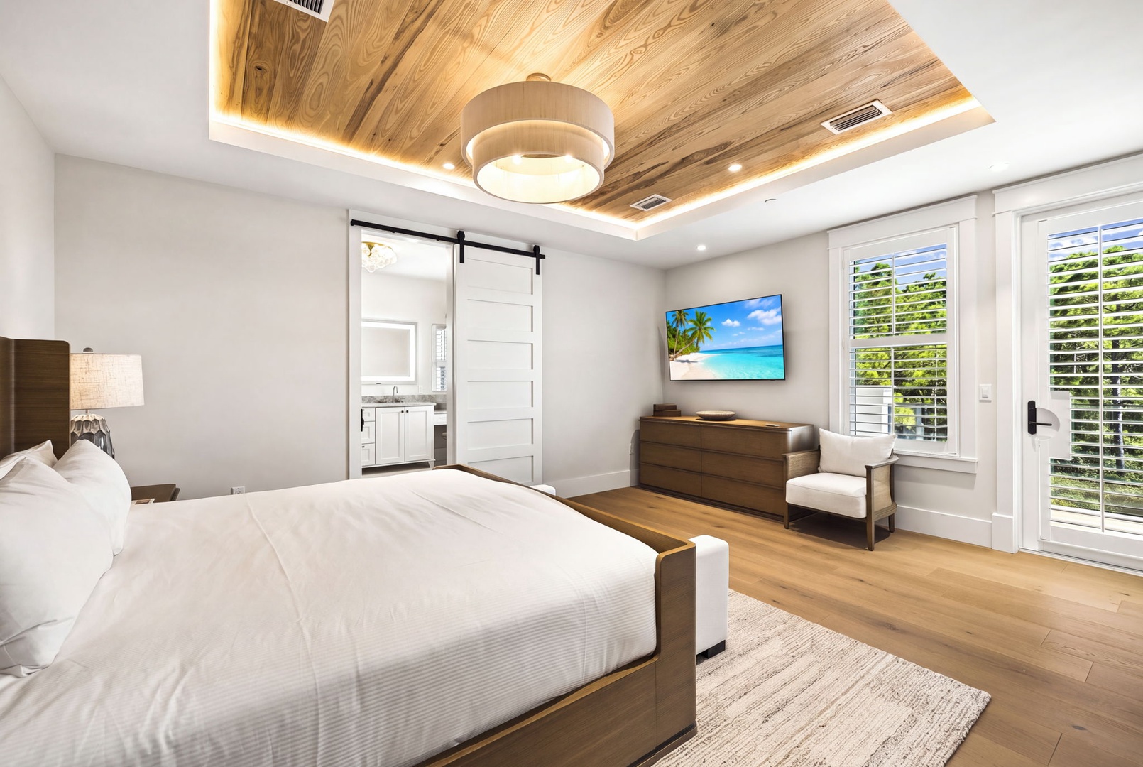 Unwind in your serene bedroom where a stunning wood ceiling and warm lighting create a peaceful retreat. Step through the elegant barn door to your private en-suite, or open the French doors to let fresh island breezes flow through your space.