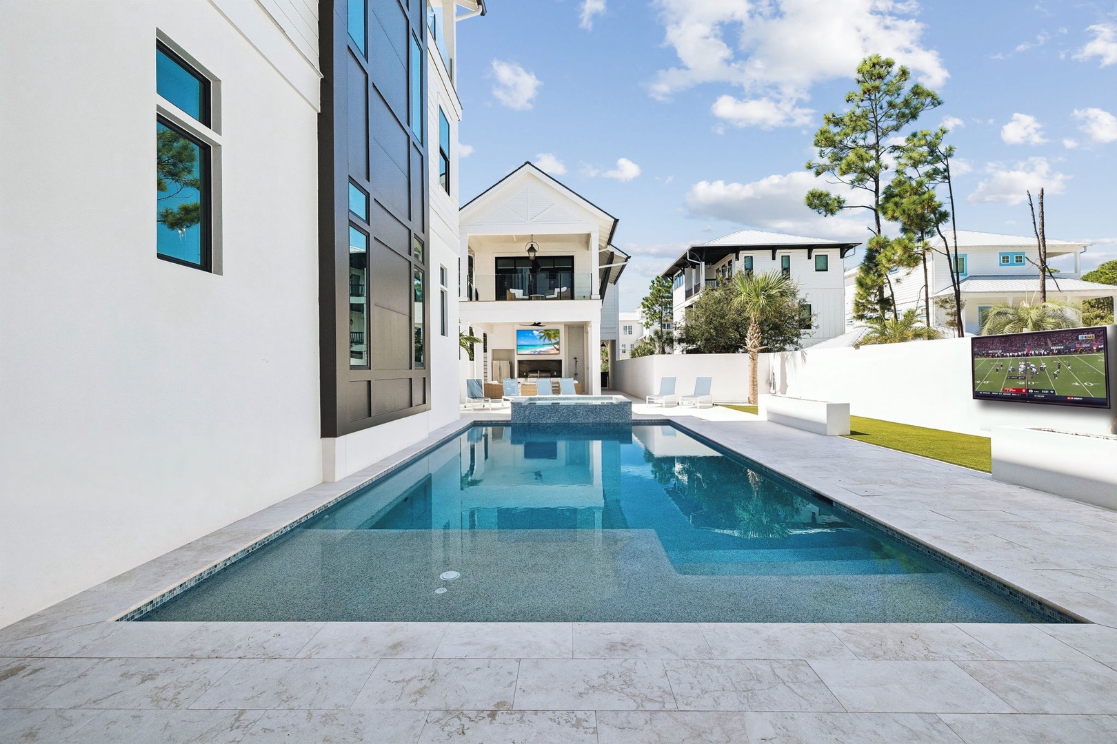 This sleek private pool features modern tile surrounds and plenty of lounge space. The property offers contemporary architecture and an outdoor entertainment area with views of the surrounding neighborhood.