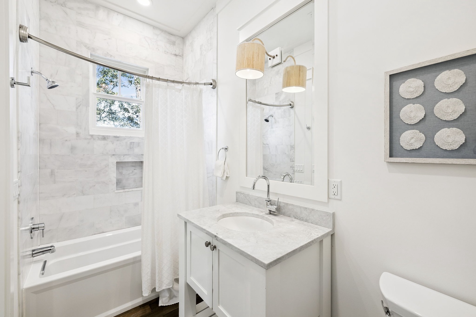 Your elegant marble bathroom features a deep soaking tub, marble vanity, and warm wood pendant lighting for ultimate relaxation.