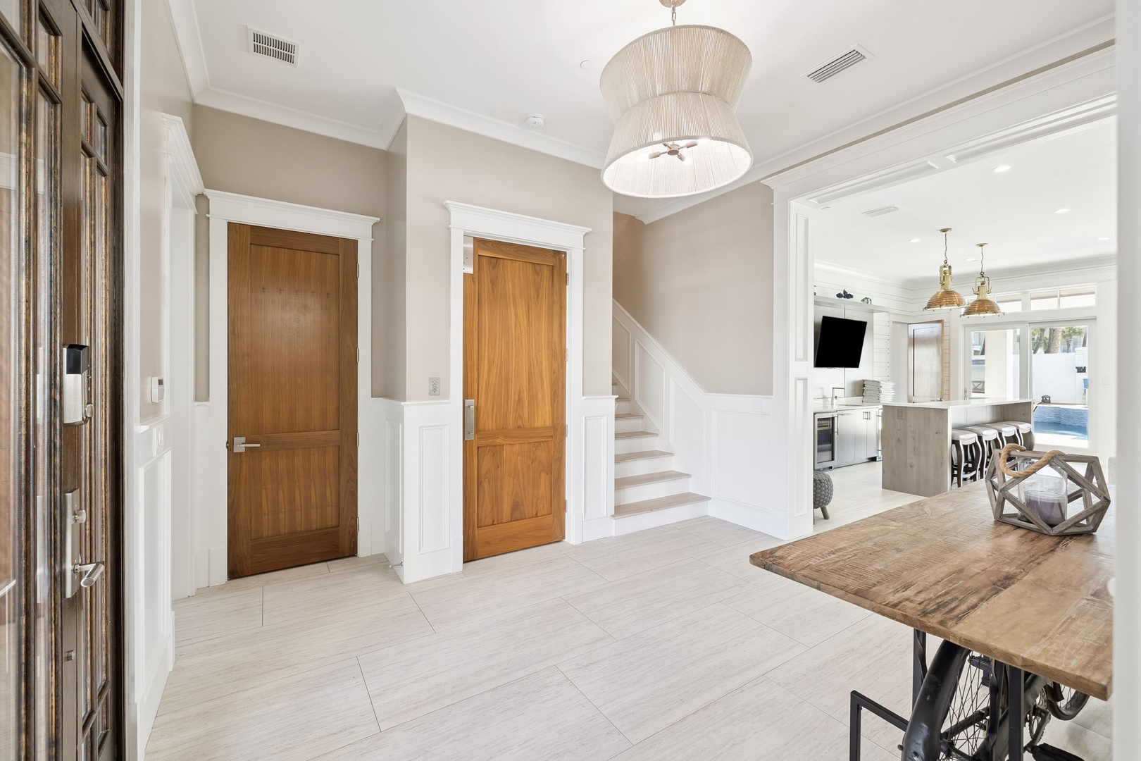 Your elegant entryway welcomes you with warm wood tones, stylish lighting, and open sightlines to the beautiful kitchen beyond.