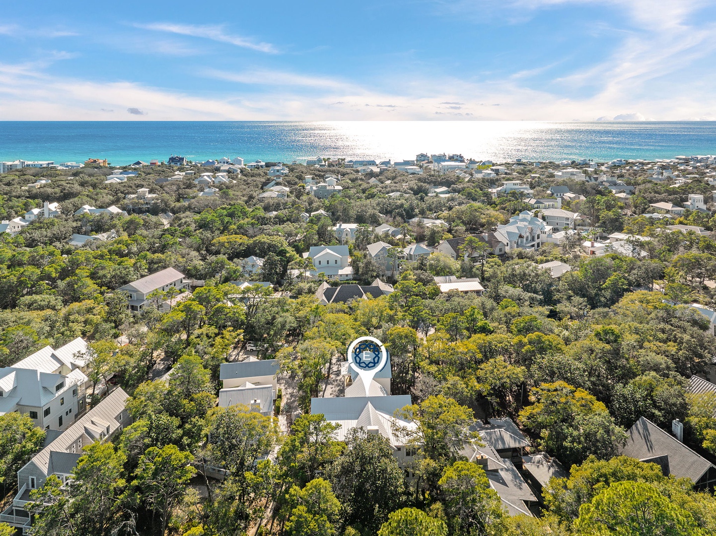 Aerial view of a coastal community nestled among lush trees, with pristine turquoise waters and sandy beaches just moments away.