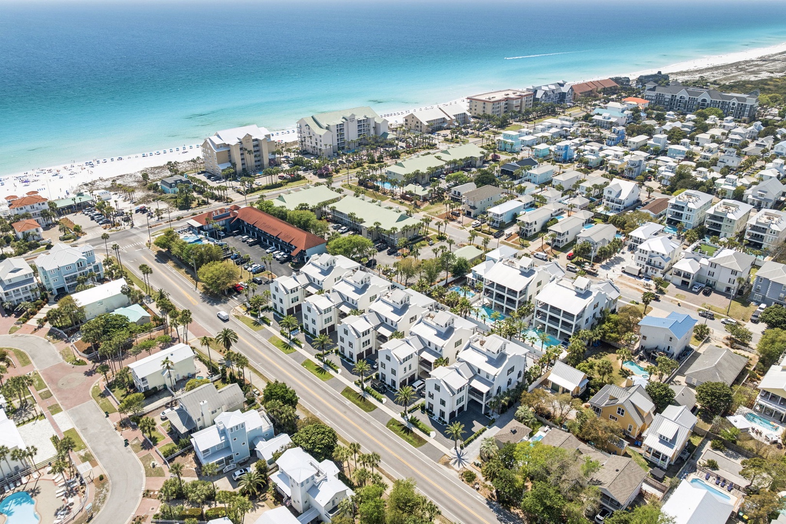 Aerial view showcasing a prime beachfront location with pristine white sand beaches and turquoise waters just steps from vacation rental properties.