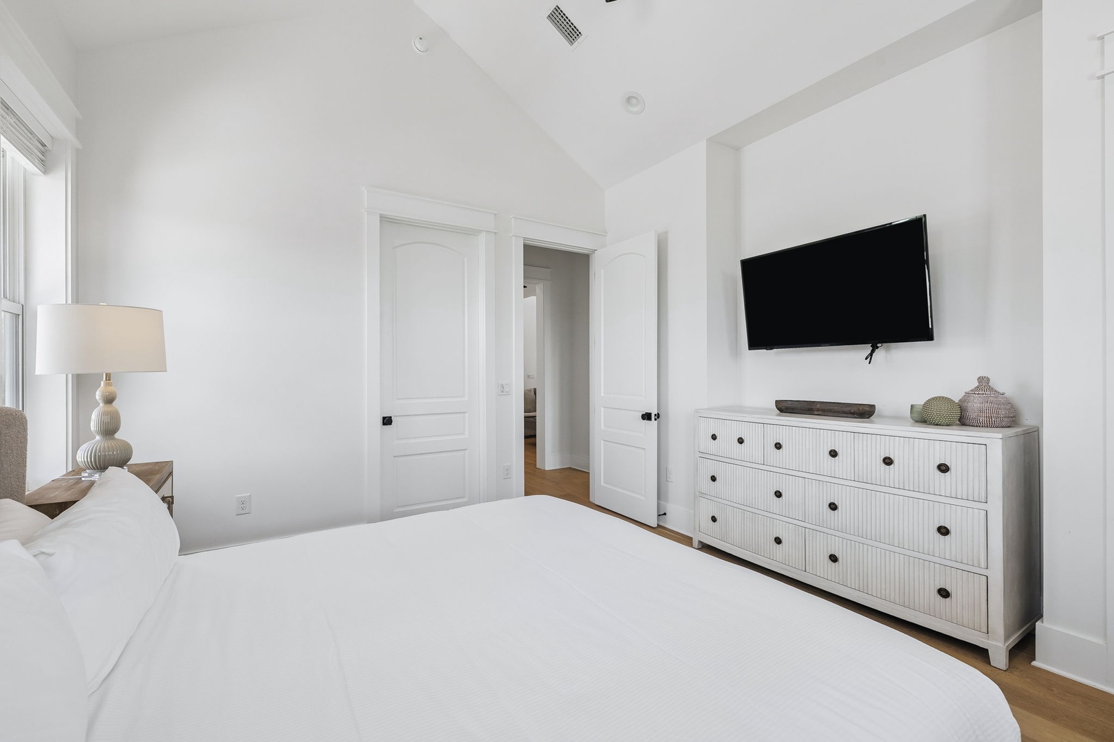 Wake up in this serene, sun-washed bedroom with crisp white linens and coastal charm. Your dresser and closet keep everything organized, while vaulted ceilings create an airy, restful retreat.
