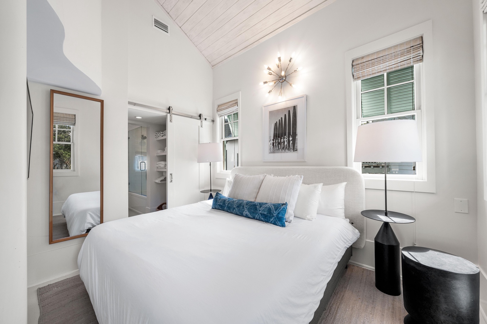 Sink into crisp white linens in your serene bedroom, where modern comfort meets coastal charm with sleek furnishings and calming blue accents.