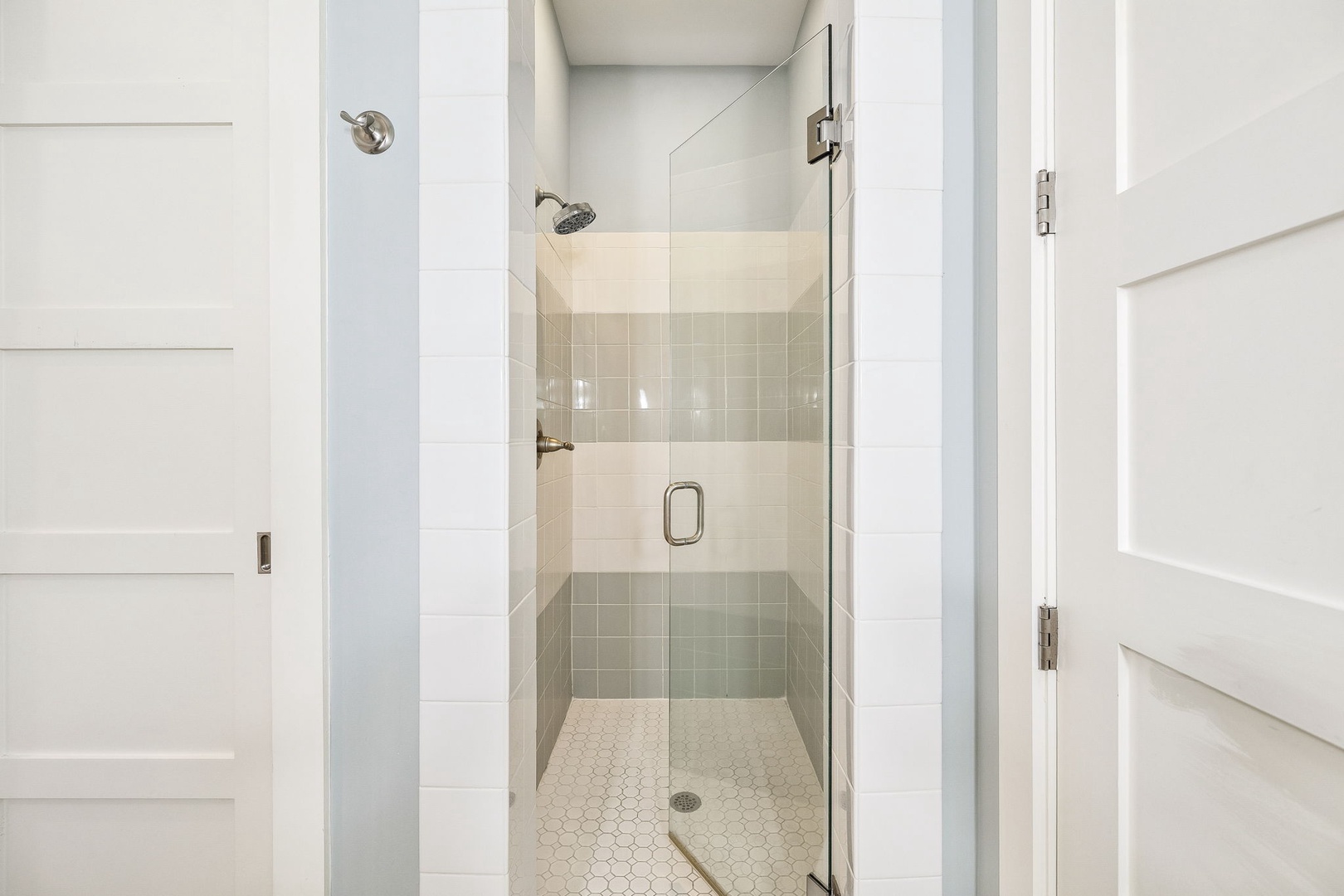 Step into your private walk-in shower, where sleek tile and a rainfall showerhead promise a refreshing start to your mornings or a calming end to your evenings.