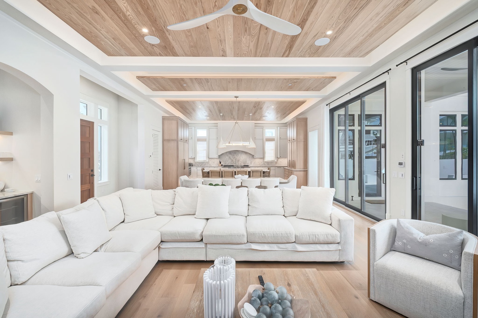 Sink into plush seating beneath stunning wood-paneled ceilings, where natural light floods your open-concept living and dining space, perfect for gathering and unwinding.