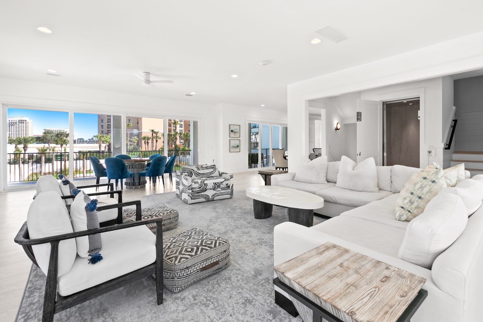 Relax in your bright, modern living space with plush seating and a view that opens onto a tranquil waterfront scene, complete with swaying palms just beyond your balcony.
