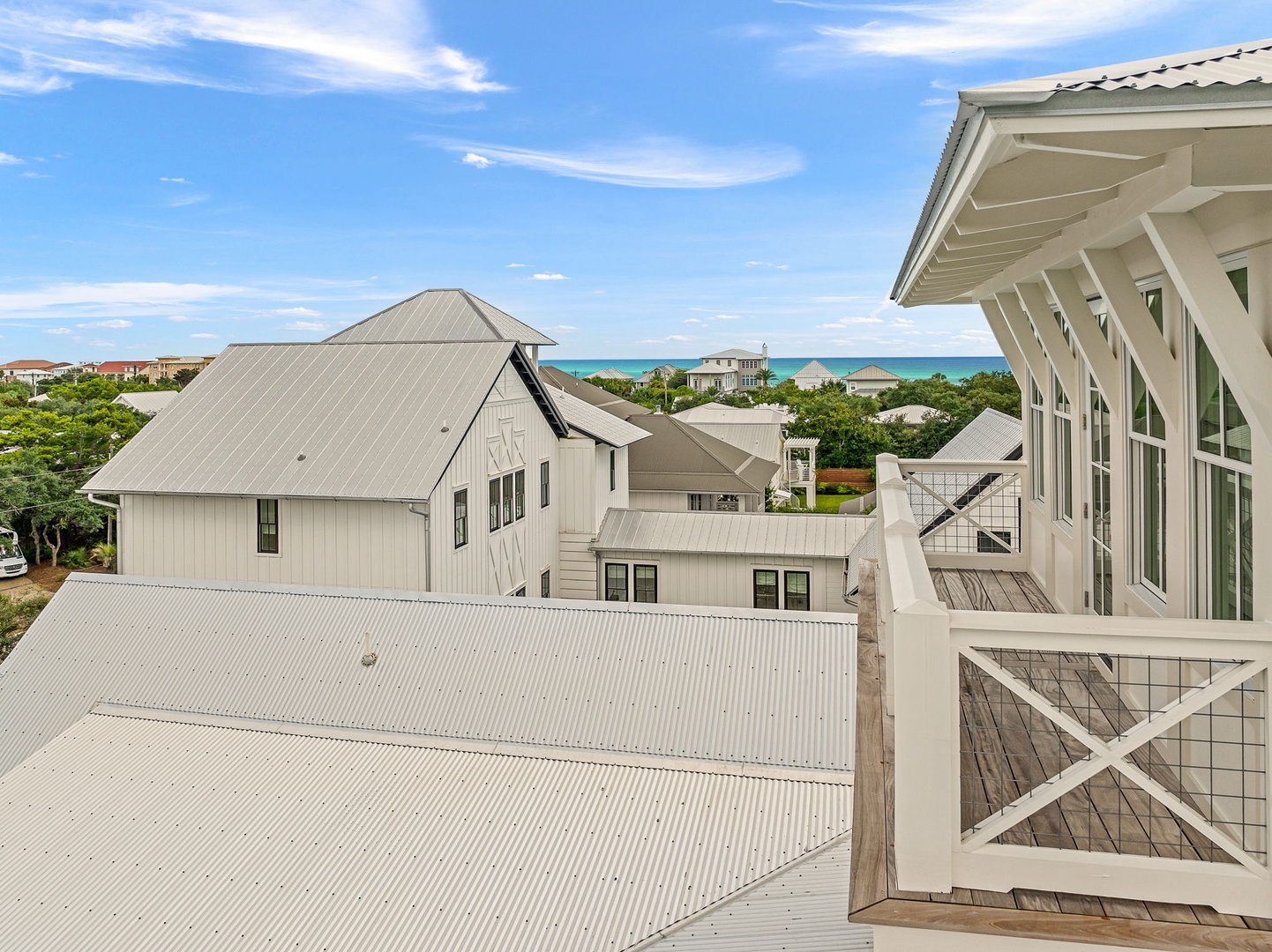 Elevated coastal property located in a beach community with ocean views visible in the distance. The home features architectural details and is situated among neighboring residences near the waterfront.