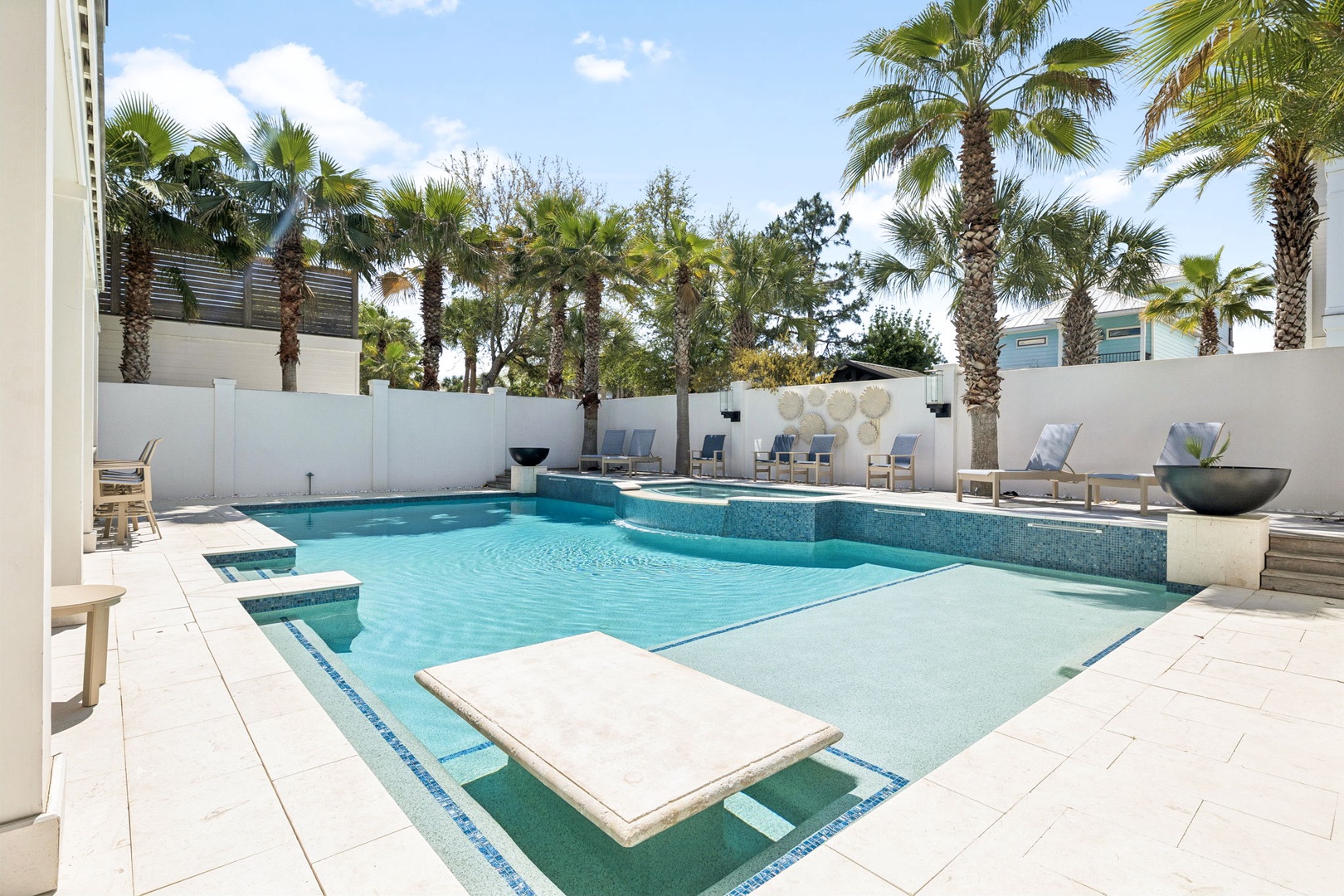 Your private oasis features a stunning swimming pool surrounded by elegant loungers and tropical palm trees.
