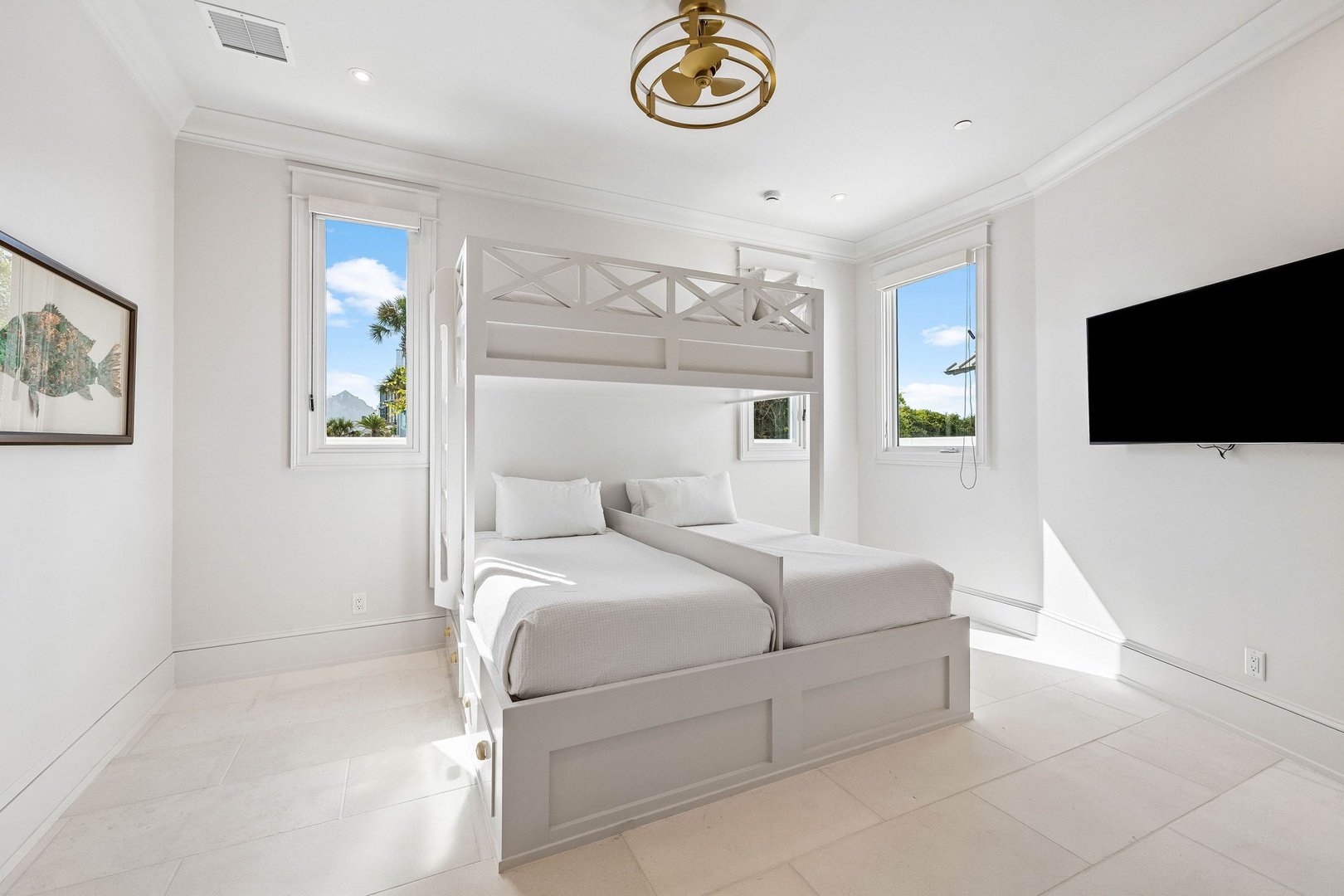 Your serene sanctuary features a plush bunk bed setup, coastal artwork, and large windows framing tropical views. Perfect for drifting off to the gentle island breeze.