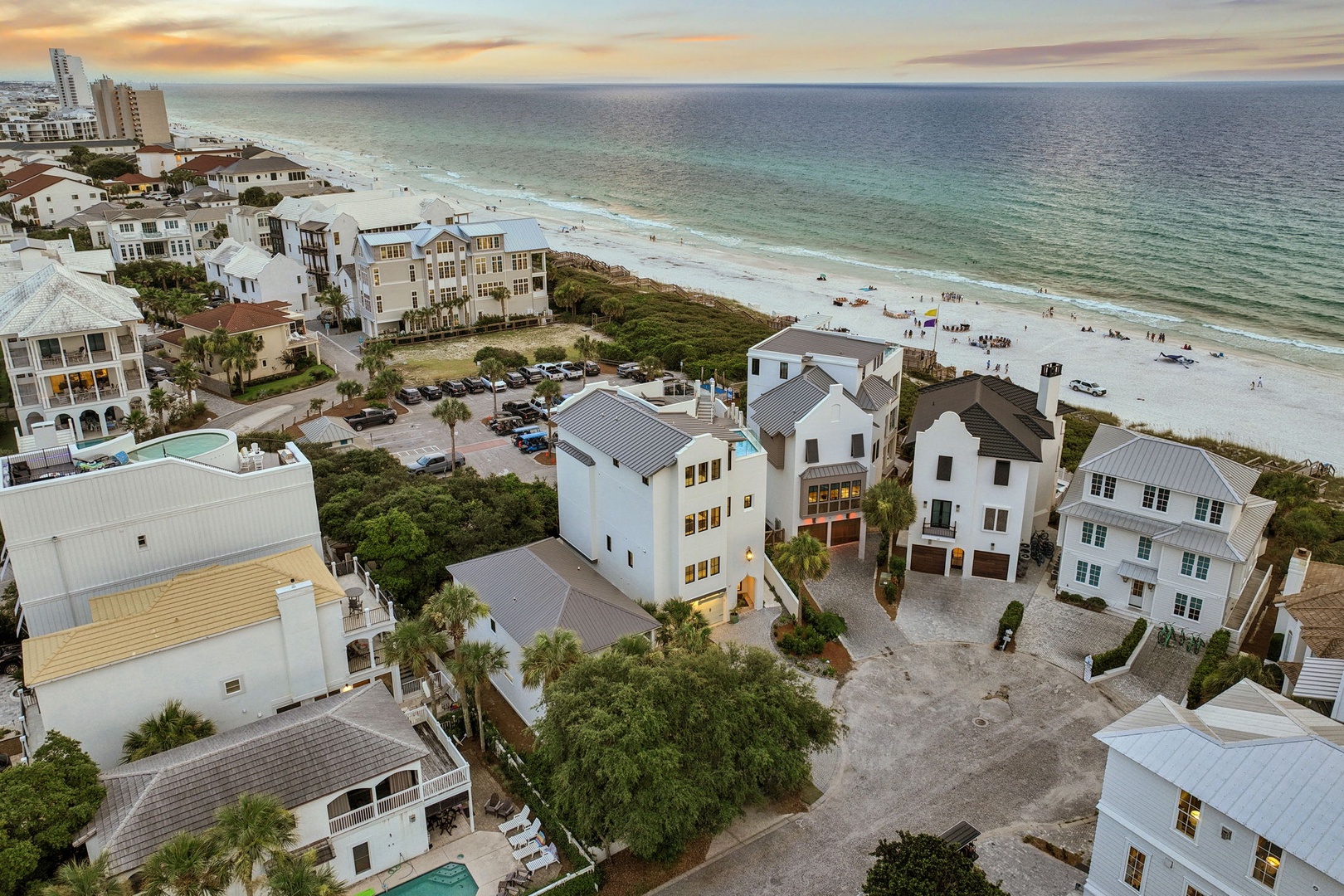 Coastal community featuring beachfront homes and vacation properties with pristine white sand beaches and turquoise Gulf waters at sunset.