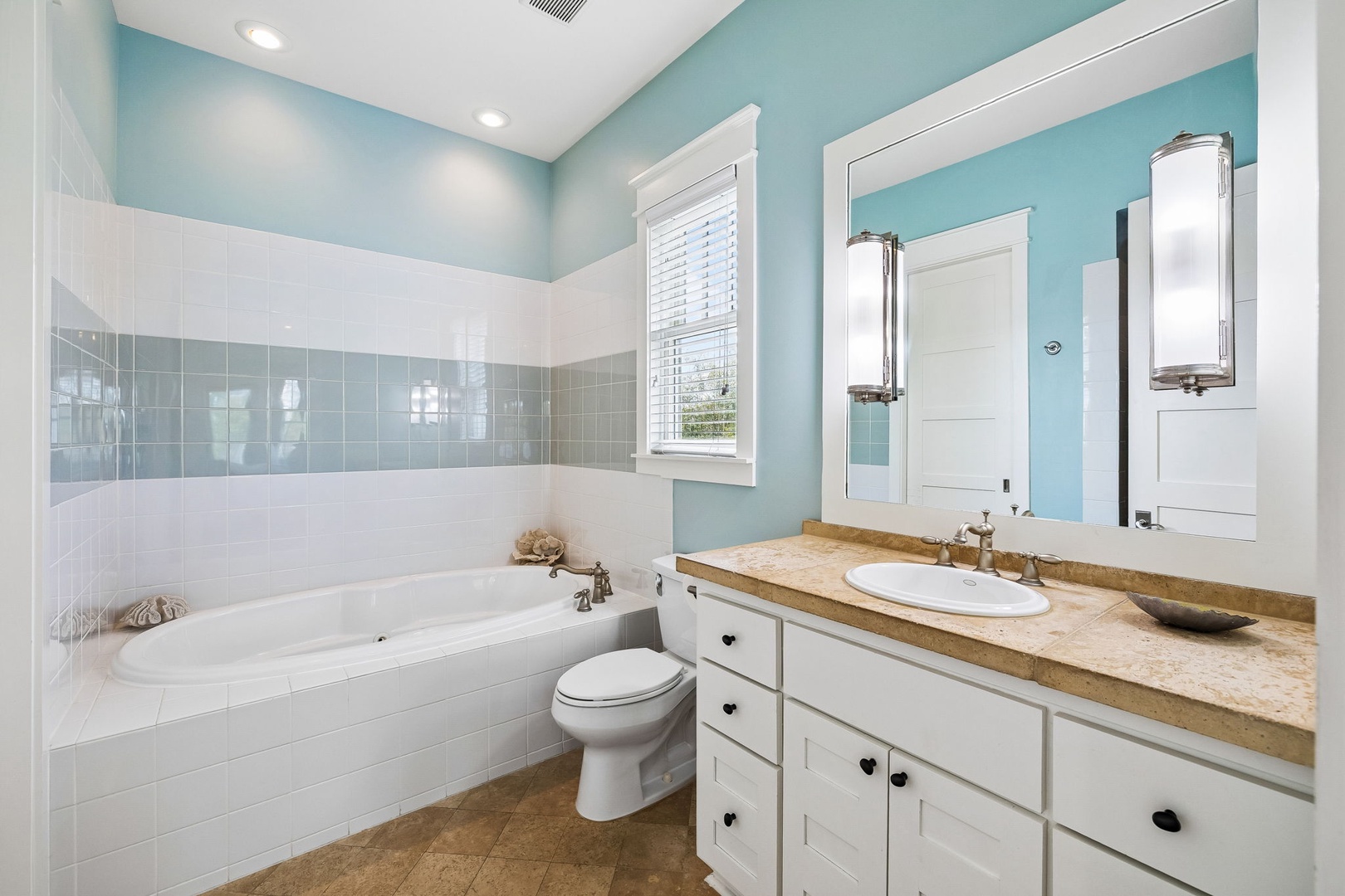 Soak your cares away in this serene spa-like bathroom, where soft blue tones and a deep soaking tub invite you to unwind after a long day exploring.